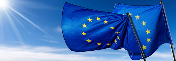 istock Two European Union Flags Blowing in the Wind on Blue Sky with Clouds 1399533552