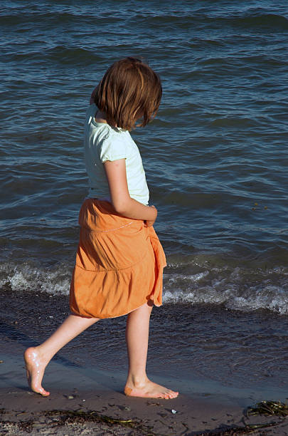 Little girl on beach Little girl in orange skirt and bare feet on beach. alintal stock pictures, royalty-free photos & images