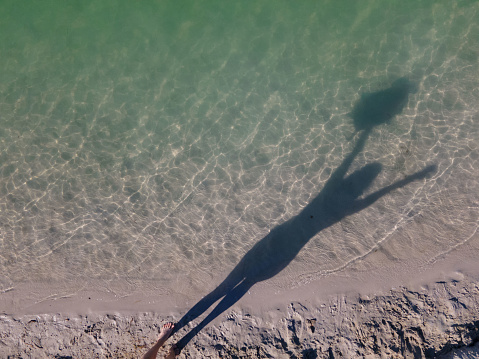 overhead view of women legs at sandy beach blue clear water copy space