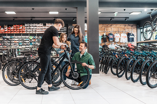 man explaining details of new bike to young family in bike shop