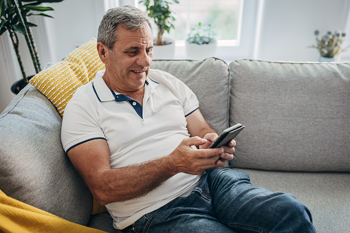 An older man uses wireless technology, a smartphone