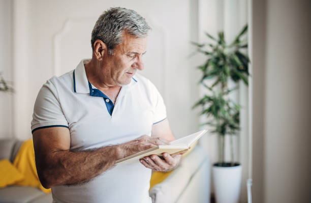 istock An older man is reading a book by the window 1399542942
