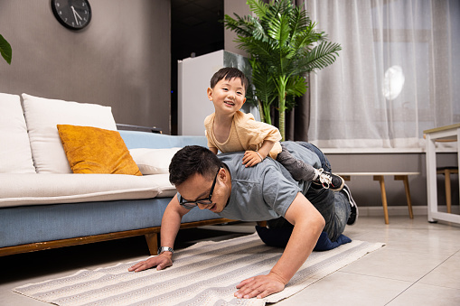 father doing push up exercise with son on back