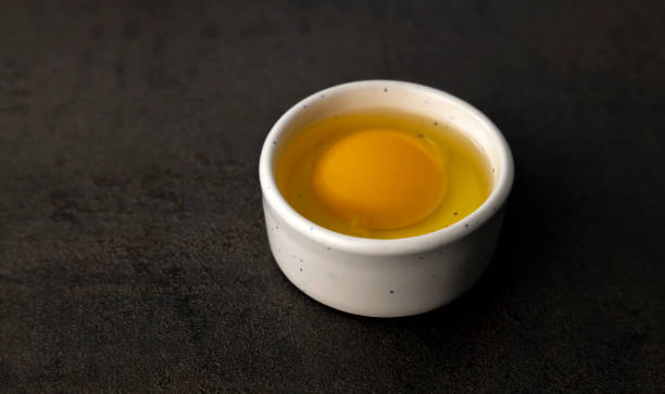 istock Bowl with a broken egg on a black background. Chicken yolk 1399546835