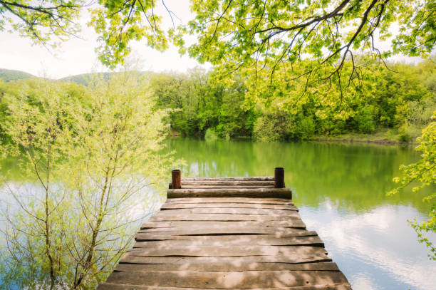 Wooden pier over the lake for fishing and relaxing on a sunny spring day, silence and relaxation, meditation and reflection