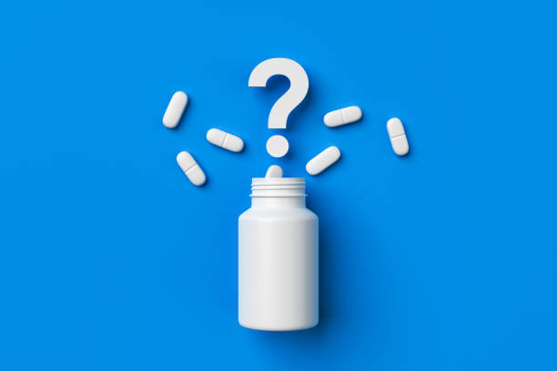 istock Plastic medical container and white capsule pills with question mark on blue background top view. 1399549569