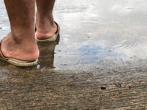 photo of feet stepping on puddles on the road