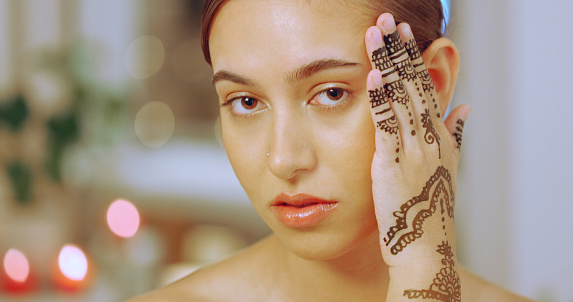 Woman showing mehndi or henna tattoo on her hands at a spa. Portrait of a young woman enjoying a relaxing day of beauty and wellness at a luxury health spa