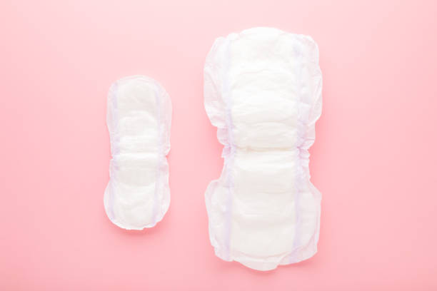 istock Two new opened white sanitary towels on light pink table background. Big and small size. Pastel color. Closeup. Hygiene product for urinary incontinence or after childbirth. Top down view. 1399554056