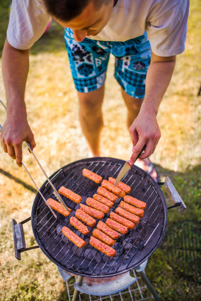 Unrecognizable men preparing the beef meat on the BBQ in the garden