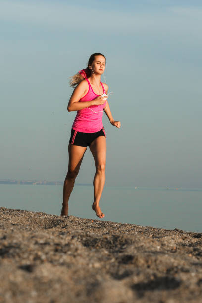 istock Athletic woman running by the sea shore 1399554739
