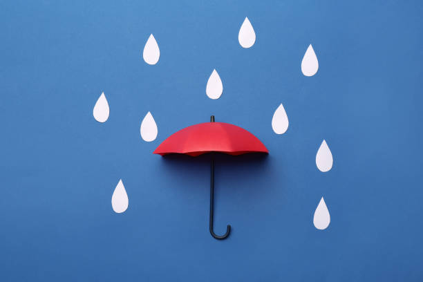 istock Mini umbrella and paper raindrops on blue background, flat lay 1399555611