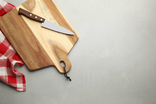istock Wooden cutting board, knife and kitchen towel on light grey table, flat lay. Cooking utensils 1399557092