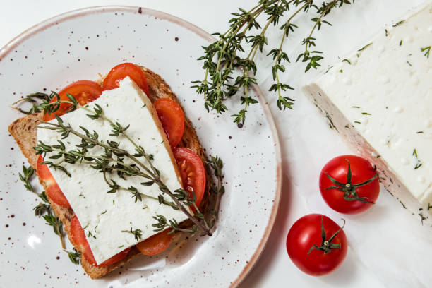 sandwichs apéritifs à la tomate cerise, fromage et herbes italiennes sur une miche de pain, fond blanc. vue de dessus - bruschetta tomato bread mozzarella photos et images de collection