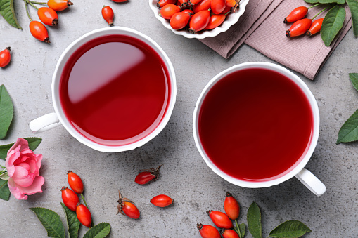 Fresh rose hip tea and berries on grey table, flat lay