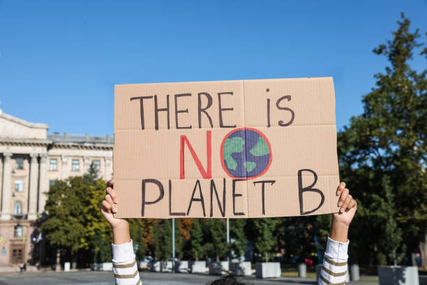 istock Young woman with poster protesting against climate change outdoors, closeup 1399558623
