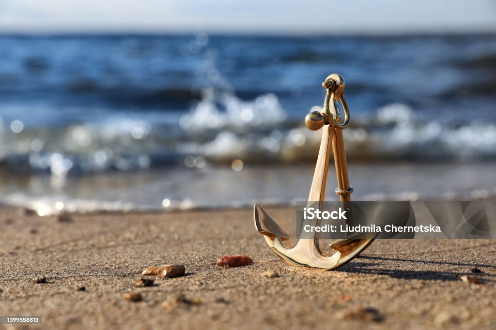 Metal anchor near river on sunny day Anchor - Vessel Part Stock Photo