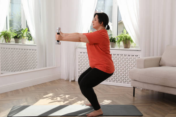 istock Overweight mature woman doing exercise with dumbbells at home 1399558857