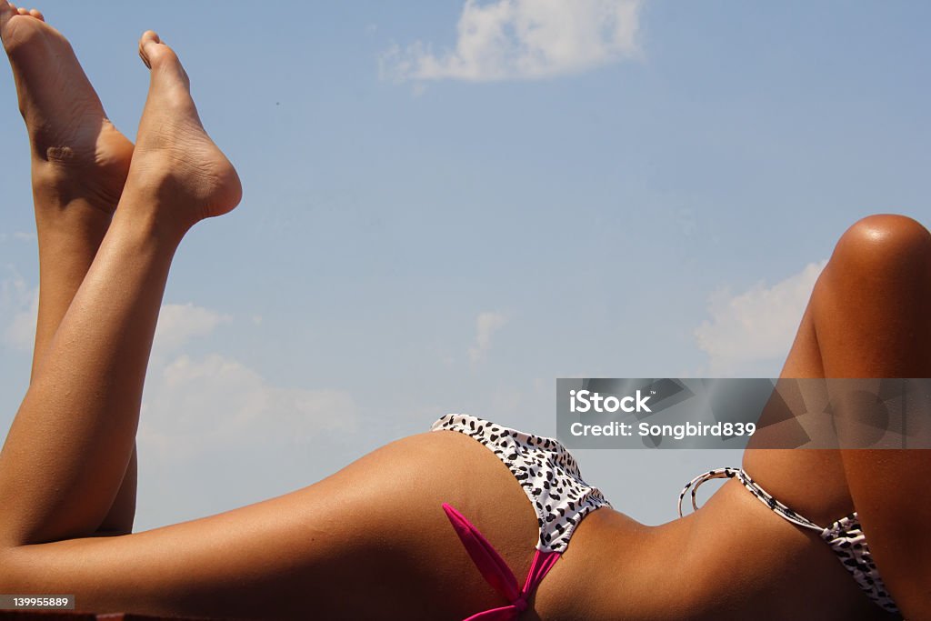 The body of a woman in a bikini tanning Girl in bikini tanning in the bright summer sun.  Room for copy. Dark Stock Photo