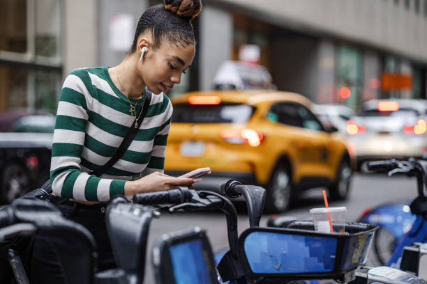 Sustainable trasportation in the city Young woman paying for a bike ride on the street rent a bike stock pictures, royalty-free photos & images