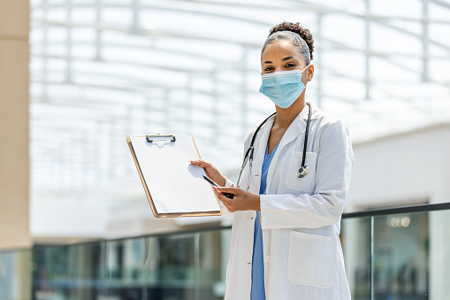 Portrait of a Latin American female doctor working and holding a clipboard while looking at the camera