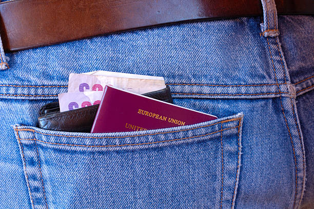 Pickpocket's delight - Wallet and passport A passport, and a wallet, containing several £20 notes, poke out of the rear pocket of someone's jeans. A temptation for a pickpocket. jeans denim passport pocket stock pictures, royalty-free photos & images