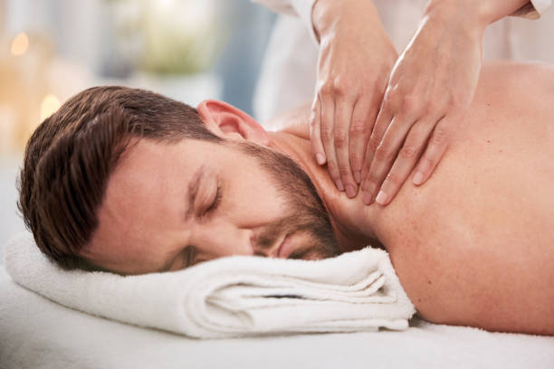 istock Handsome caucasian man lying on a table at the spa for his back massage. Shirtless man relaxing in a day spa getting pampered by the masseuse. Handsome customer under a towel ready for his rub down 1399560974