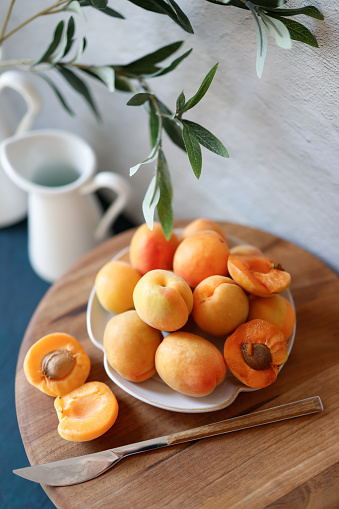 Istanbul, Turkey-May 16, 2022: Ripe apricots in a white ceramic plate on a walnut wooden presentation board. Shot with Canon EOS R5.