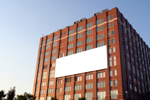 An empty billboard on a brick building.