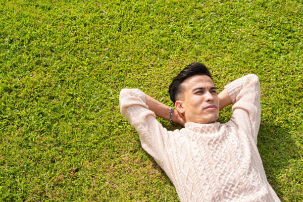 istock Handsome young man laying down on grass during summer at park 1399562309