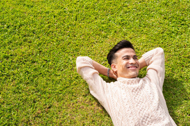 istock Handsome young man laying down on grass during summer at park 1399563128