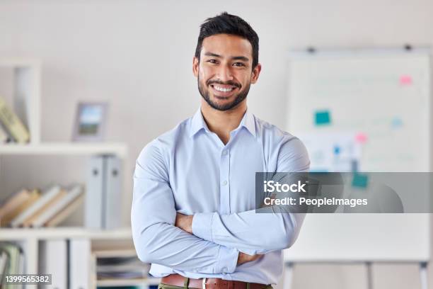 Young Happy Mixed Race Businessman Standing With His Arms Crossed Working Alone In An Office At Work One Expert Proud Hispanic Male Boss Smiling While Standing In An Office Stock Photo - Download Image Now