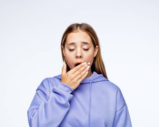 Teenage girl yawning against white background Tired teenage girl in t-shirt yawning against white background. yawning stock pictures, royalty-free photos & images