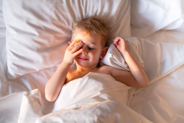istock Pretty toddler boy just woke up and basking in bed. 1399570385