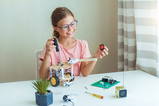 Smart little caucasian girl learn at home in coding robot cars and electronic board cables in STEM, mathematics engineering science technology computer code in robotics for kids concept