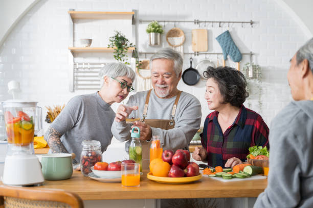 Group of Asian senior people friends making fruit juices for friends to drink in kitchen.colorful fruits and vegetables. Healthy eating stock photo
