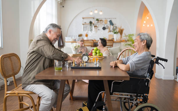 porträt von zwei asiatischen älteren männern, die schach spielen und im pflegeheim - play time stock-fotos und bilder