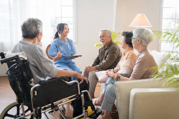 Group of Asian senior people sit in a circle in a nursing home and listen to nurse during a group elderly therapy session. stock photo