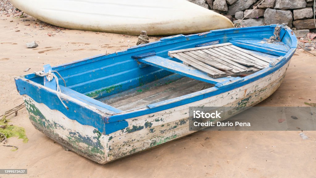 Weathered boat Weathered white and blue wooden boat in a sand beach Nautical Vessel Stock Photo