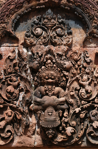 Red stone carving of the Monster abducting Sita, the wife of Shiva, in the Banteay Srei Temple in the Angkor Area near Siem Reap, Cambodia.