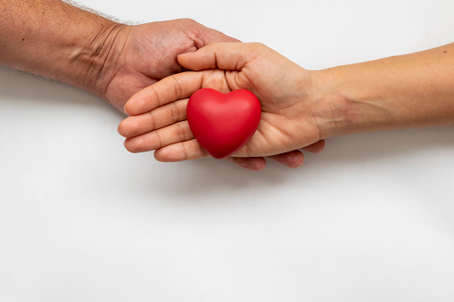 woman's hand with red heart supported by man's hand