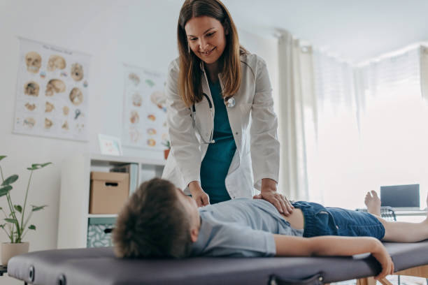You will be fine Female doctor is examining young boy' s stomach and intestines on the medicinal table gastroenterology photos stock pictures, royalty-free photos & images
