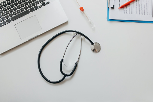 Photo of laptop, cotton swab and stethoscope on the table