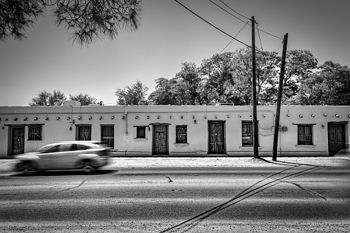 A car's blurred motion as it passes an old building in rural Socorro, Texas just east of El Paso, Texas.