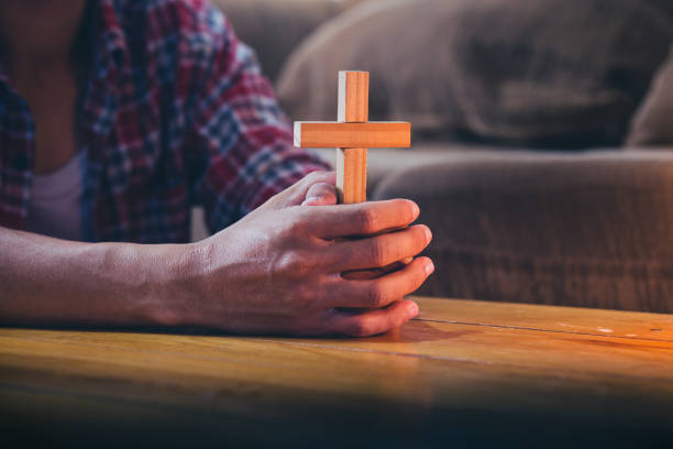 istock Man holding wooden cross praying with light candle. 1399579406