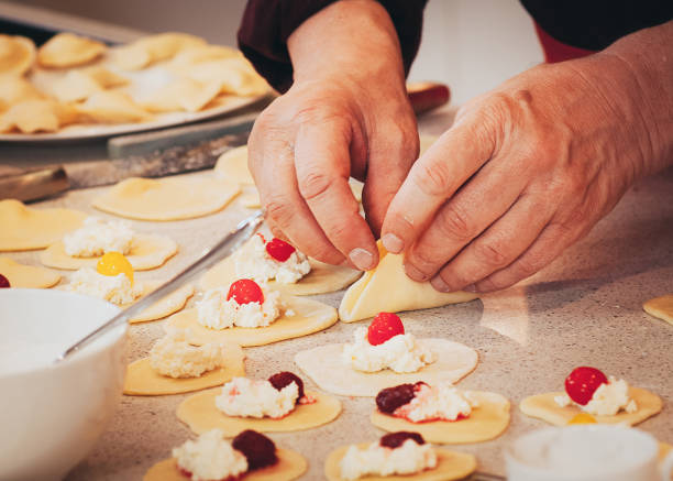 hands preparing cheese and cherry dumplings - domestic kitchen senior adult built structure candid imagens e fotografias de stock