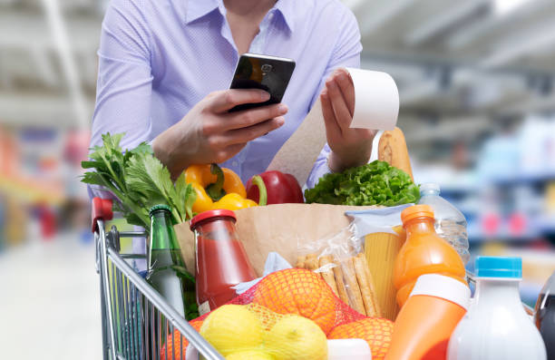 woman checking the grocery receipt - huishoudkosten stockfoto's en -beelden