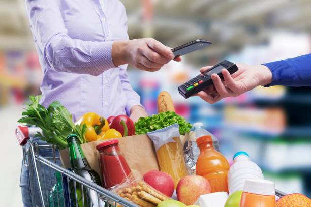 Woman paying for groceries using her smartphone stock photo