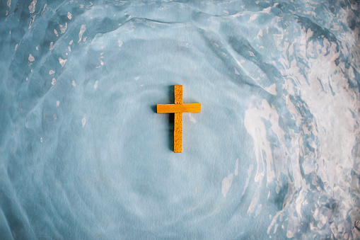 Cruz de madera rodeada de agua bautizada por Cristo photo