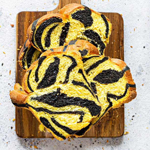 istock Unusual pumpkin marbled (tiger print) bread with cuttlefish ink, braided on a wooden board on a light background. 1399584887